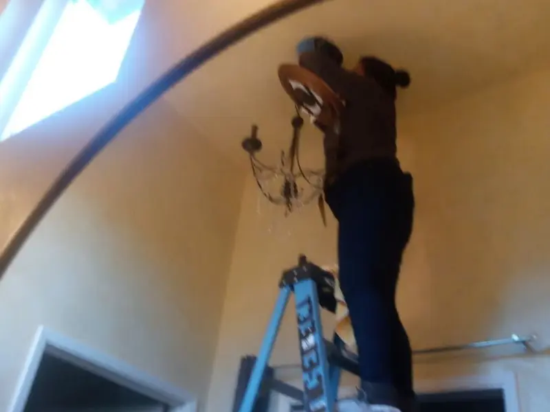 Electrician installing a chandelier in a Warren residence